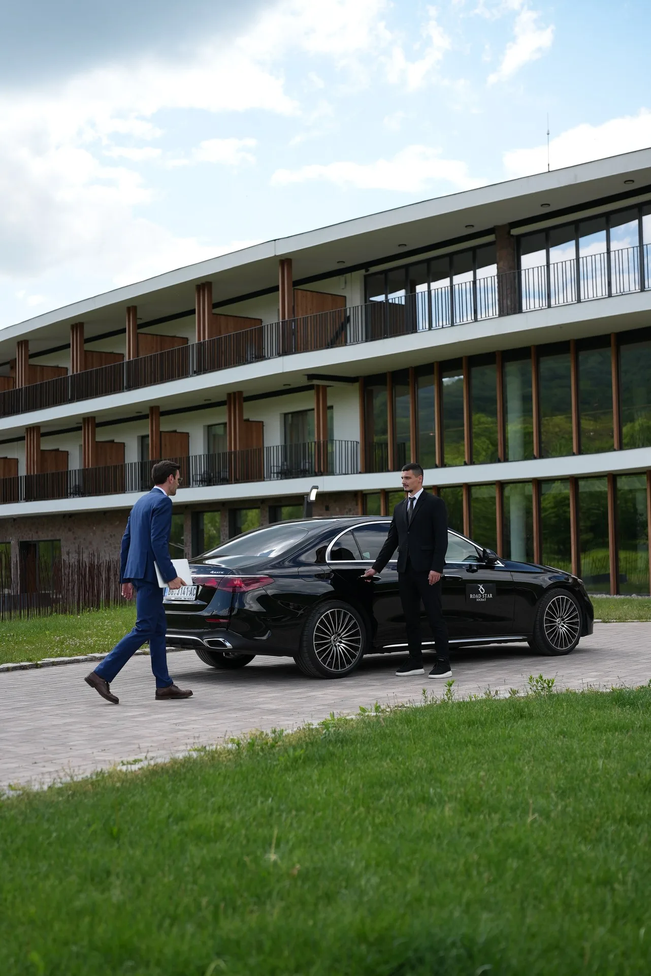 A Socrat Road Star chauffeur opening the door of a Mercedes S-Class for a client